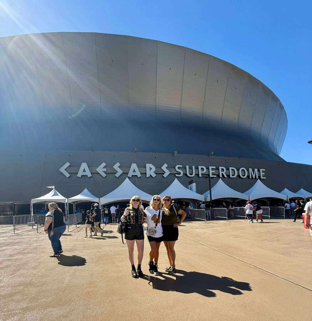 Three women pose in front of Caesar's Superdome in New Orleans, LA.