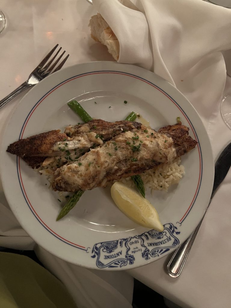 Crabmeat Crusted Redfish with asparagus and a lemon slice on a plate at Antoine's restaurant in New Orleans.